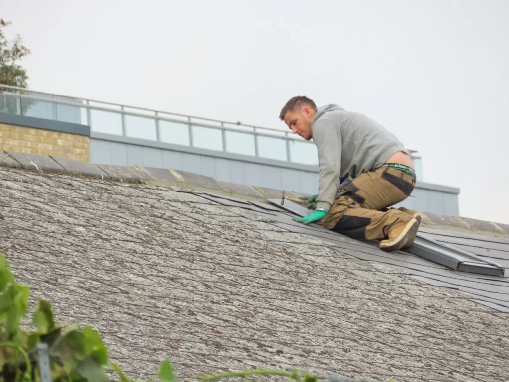 Professional roofer installing asphalt shingles on a brick home roof in Allen Texas during a roof leak repair