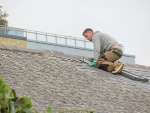 Professional roofer installing asphalt shingles on a brick home roof in Allen Texas during a roof leak repair
